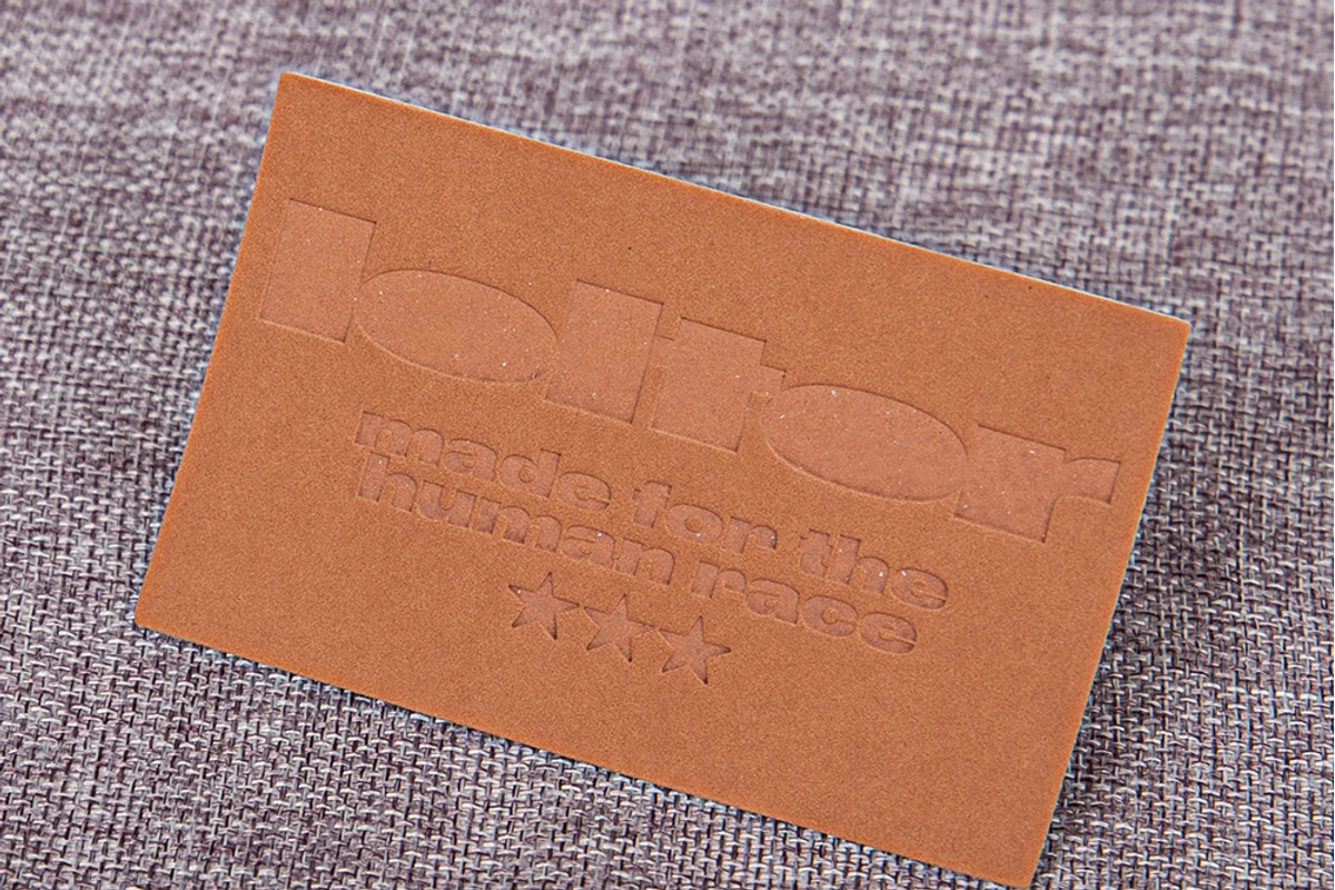 A rectangular impressed label on a textured fabric surface.