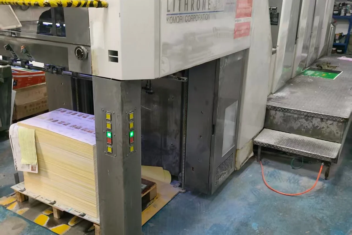 A paper printing press with a stack of printed sheets.
