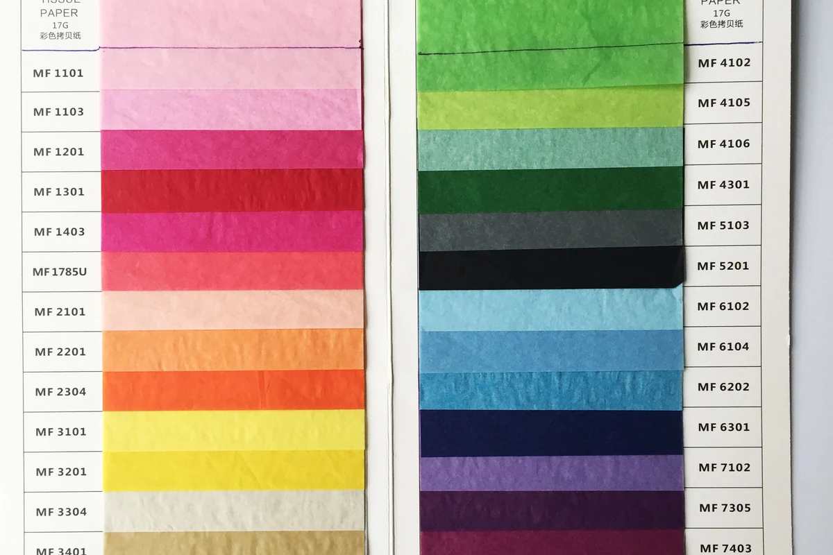 Close-up of colored tissue paper samples in a material swatch book.