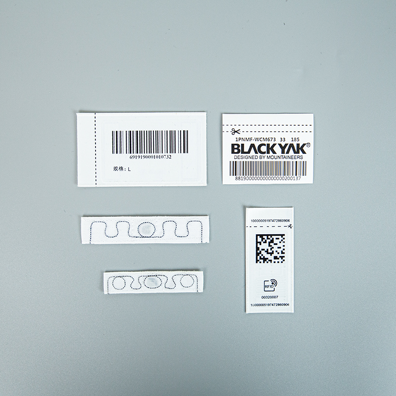 Printed linear barcode labels beside a Data Matrix label and exposed RFID antenna samples.