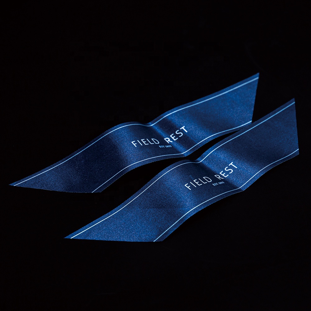 Two long blue printed fabric labels with white lettering and borders.