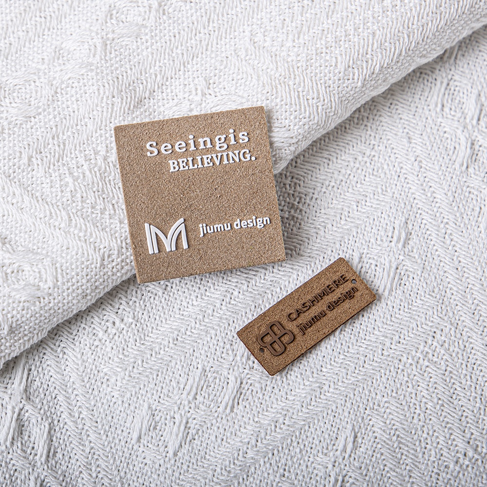 Square and narrow brown brand labels displayed on cream knit fabric.