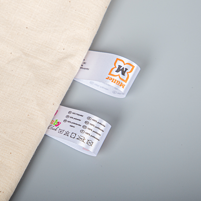 White folded labels with printed composition text and care symbols beside cream fabric.