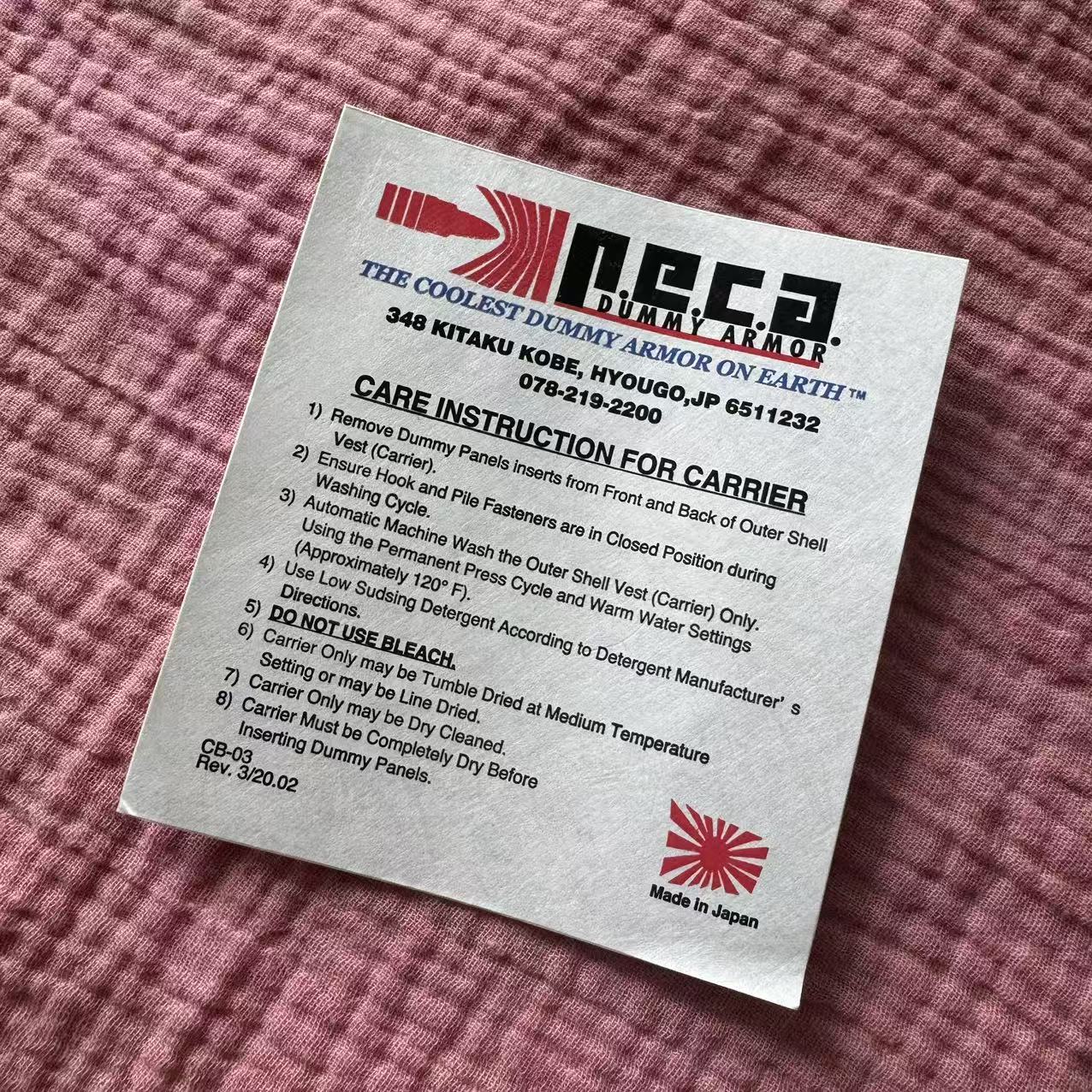 A white adhesive care-information label with several lines of black print on textured pink fabric.