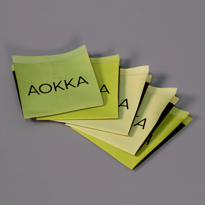 Green and cream fabric labels with black lettering and folded construction.