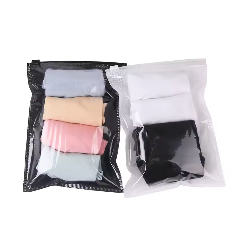 Two clear-front packing bags holding folded clothing in different colors.