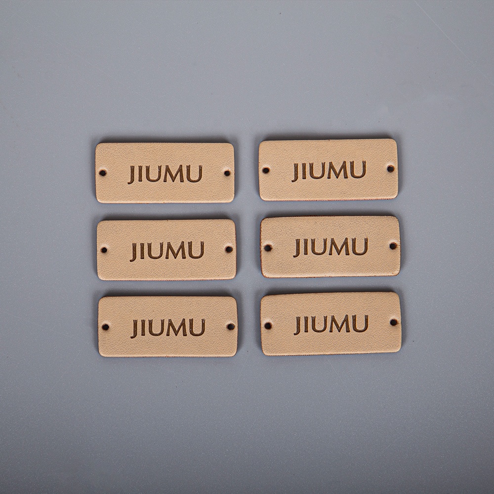 Six tan rectangular leather-look labels with rounded corners, dark lettering and end holes.