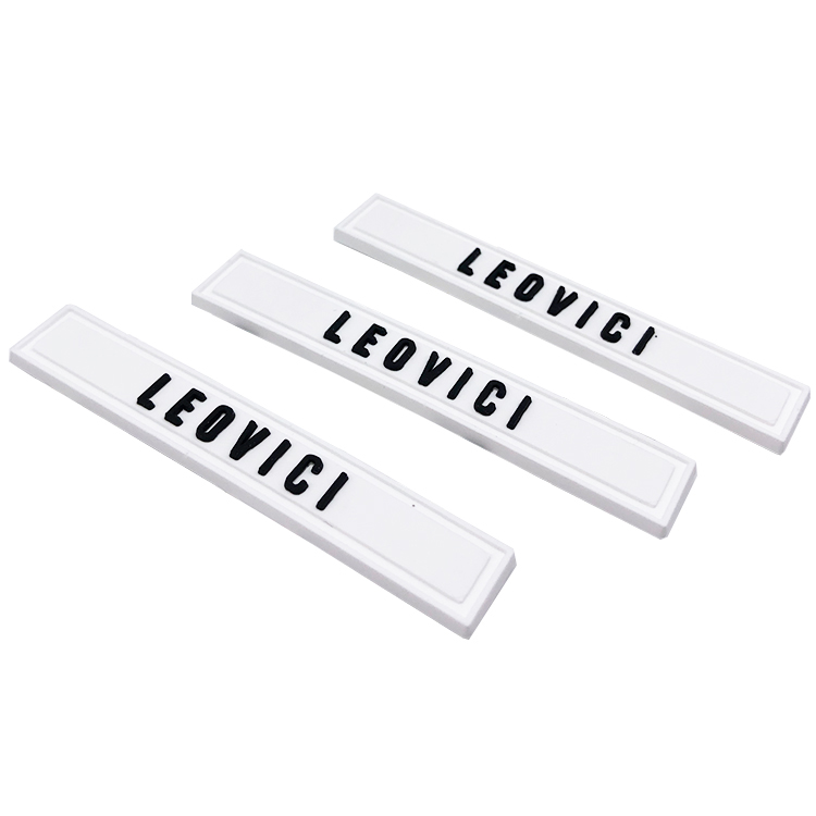Three white rectangular molded labels with raised black lettering and narrow borders.