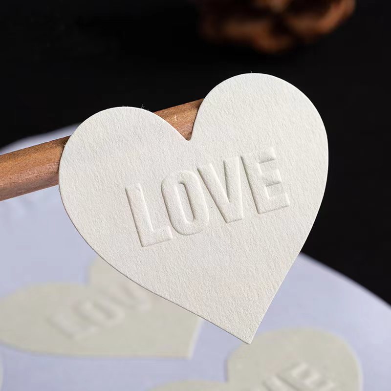 Heart-shaped white paper sticker with the word LOVE embossed on its face.