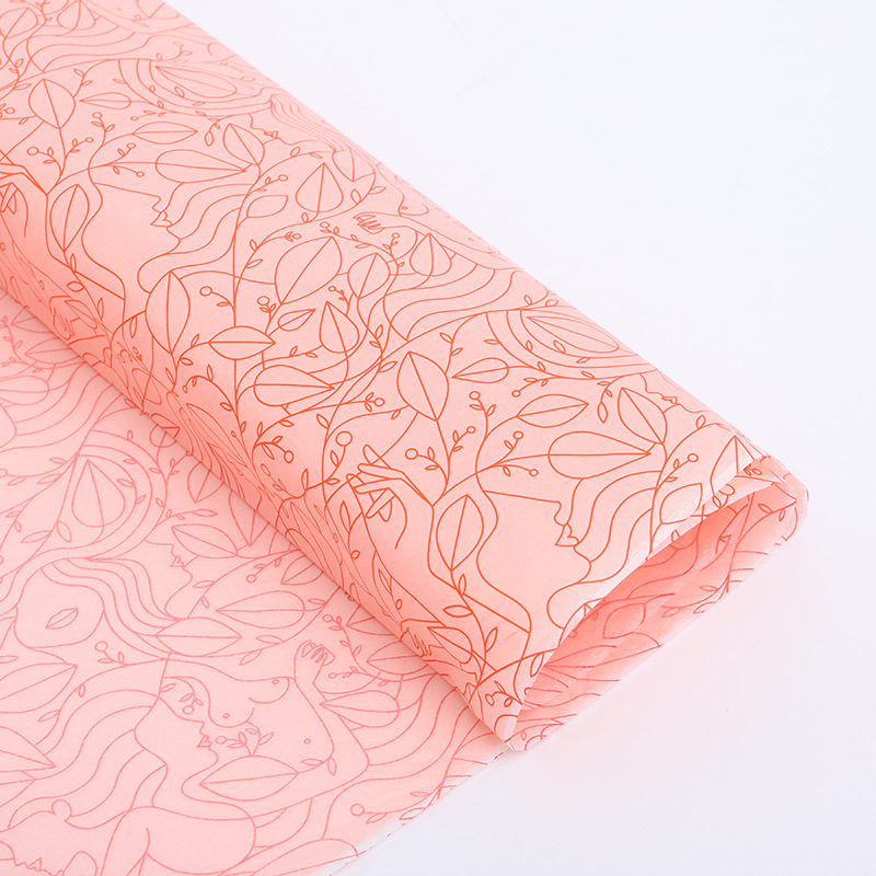 Pink tissue paper with a repeating red line pattern, partly rolled on a white surface.