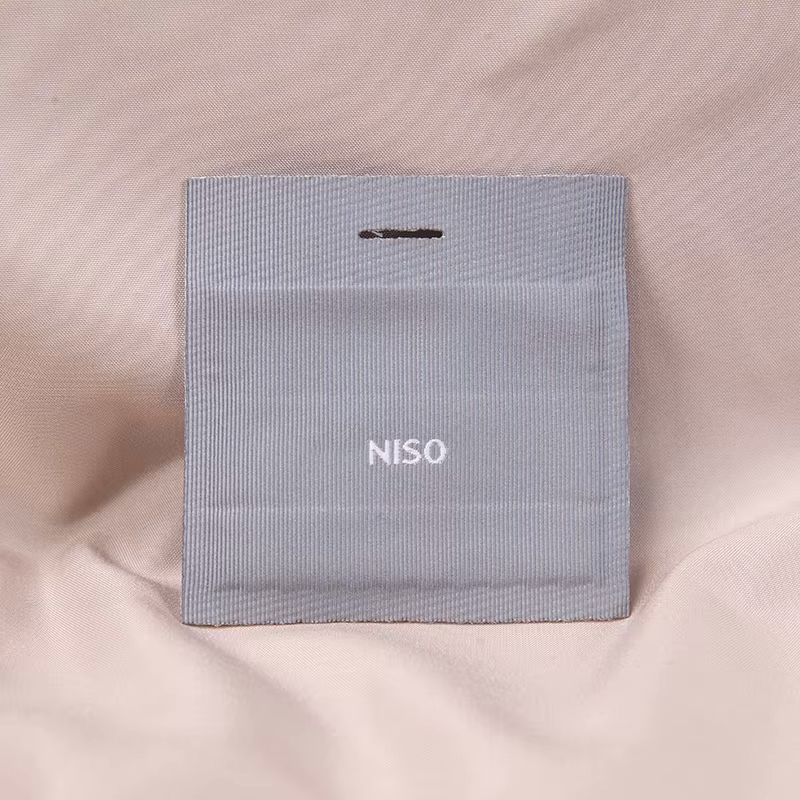 A gray fabric label with a small white wordmark and space around the design.