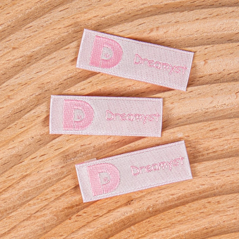 Pink woven brand labels with folded ends.