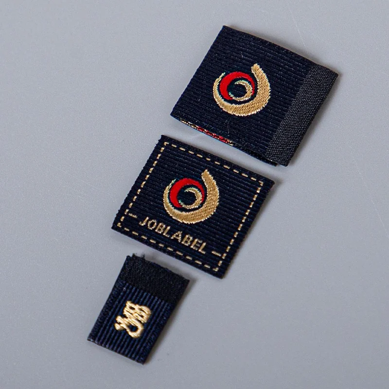 Small square fabric brand labels with bordered designs.