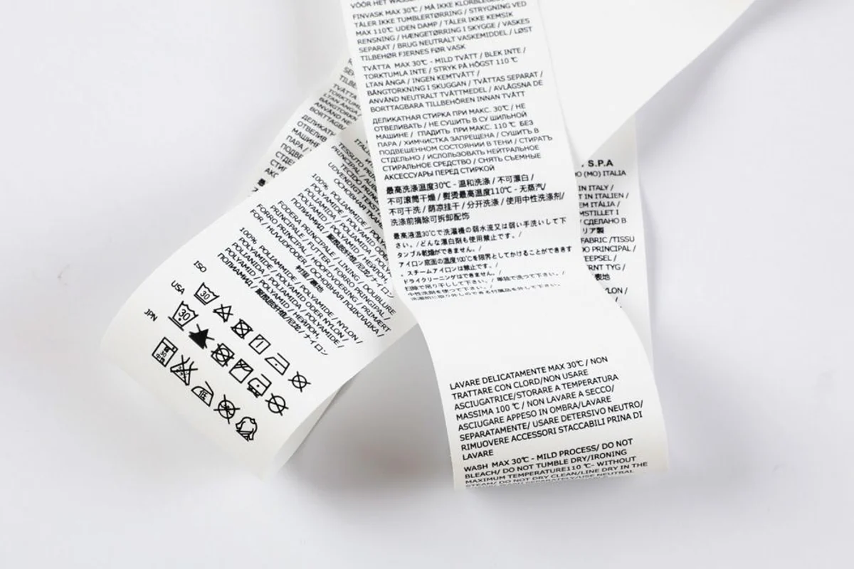 Multilingual printed care labels arranged loosely.