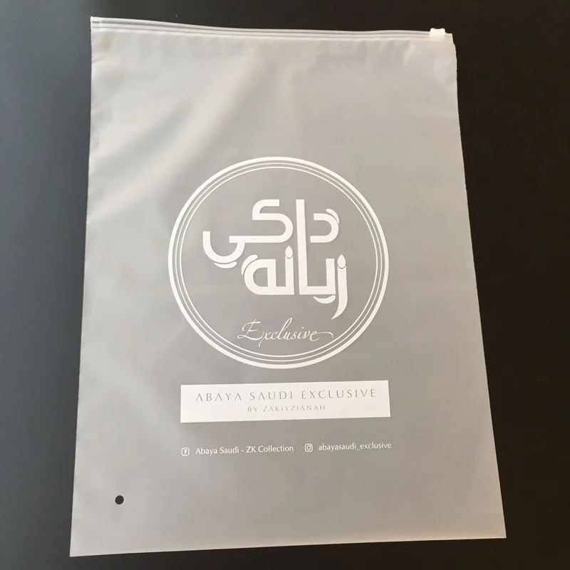 A frosted garment bag with white printed branding on a dark surface.