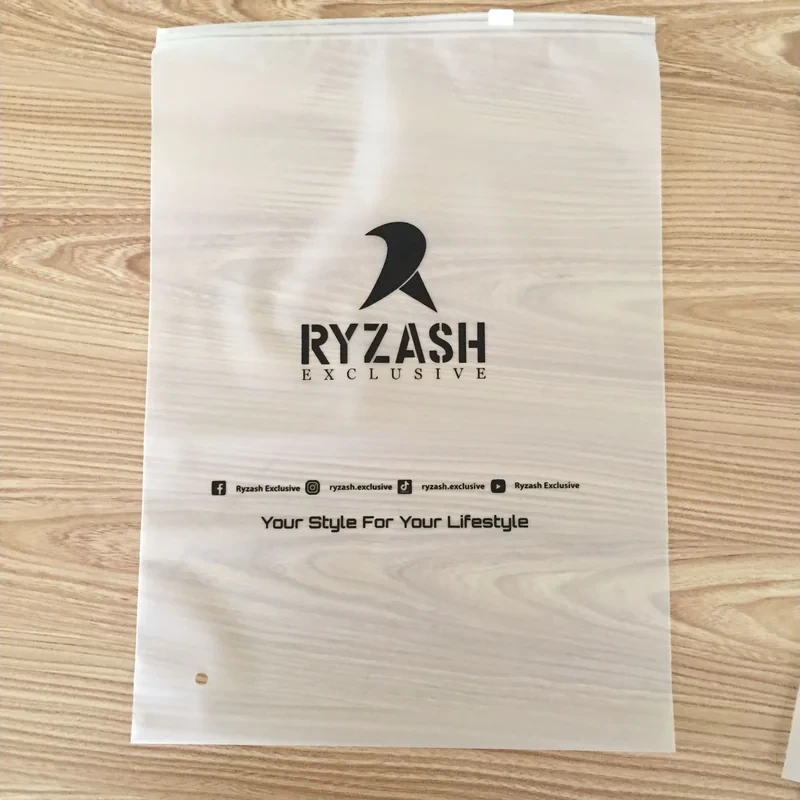 A frosted zipper bag with black logo artwork on a wood surface.