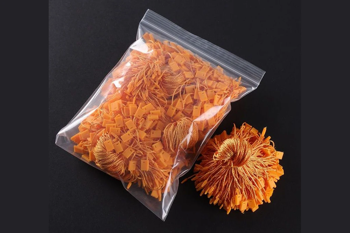 Orange tag cords packed in a clear bag beside a tied bundle.