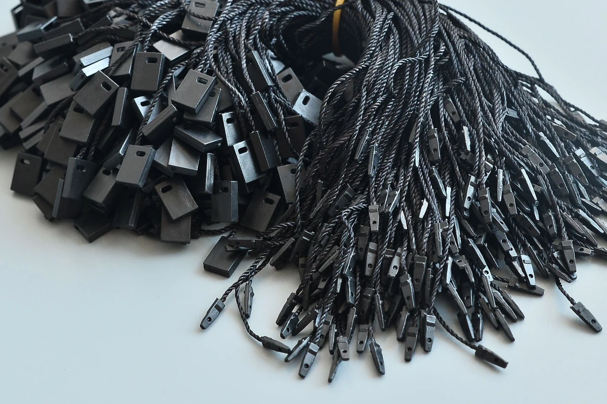 Close-up of finished black tag cords, rectangular locking pieces and separate end fittings.