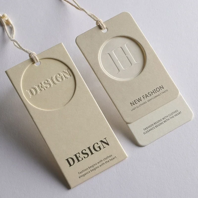 Two finished cream hang tags showing impressed lettering and circular details.