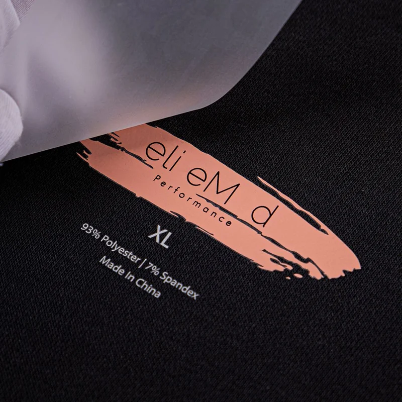 Matte peach-colored logo transfer on black fabric.