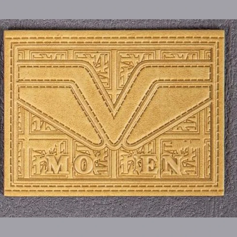 A gold-toned leather label with detailed logo artwork.