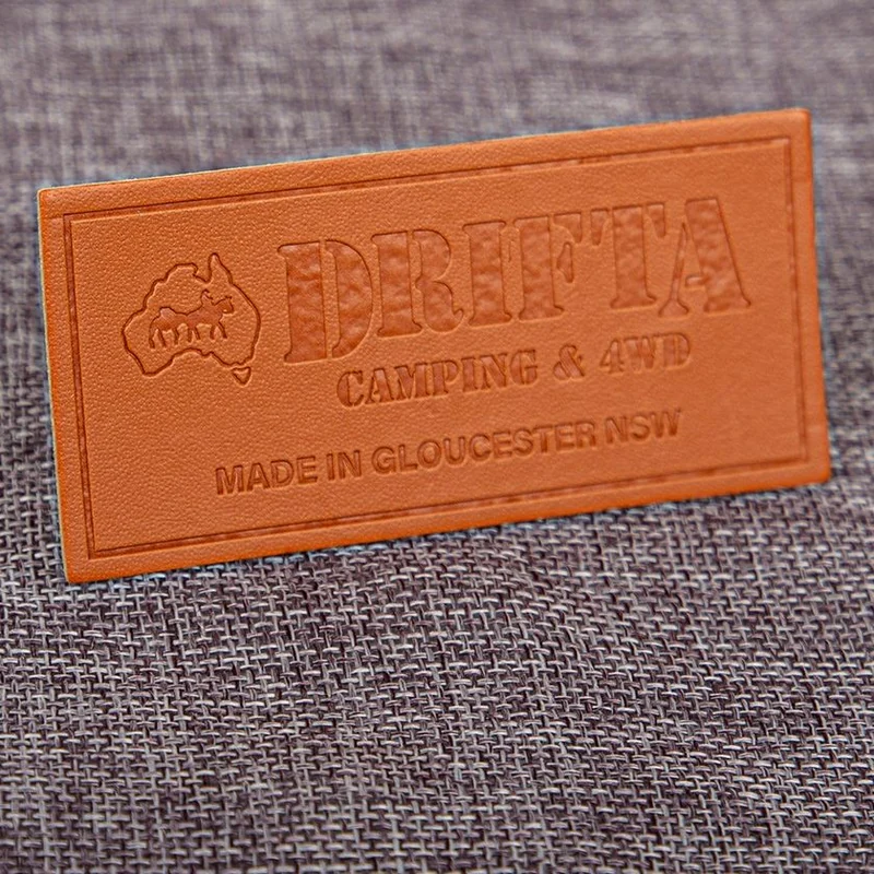 A brown rectangular label with an impressed logo.