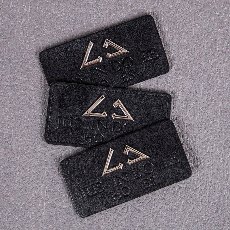 Black leather labels with metallic logo details.