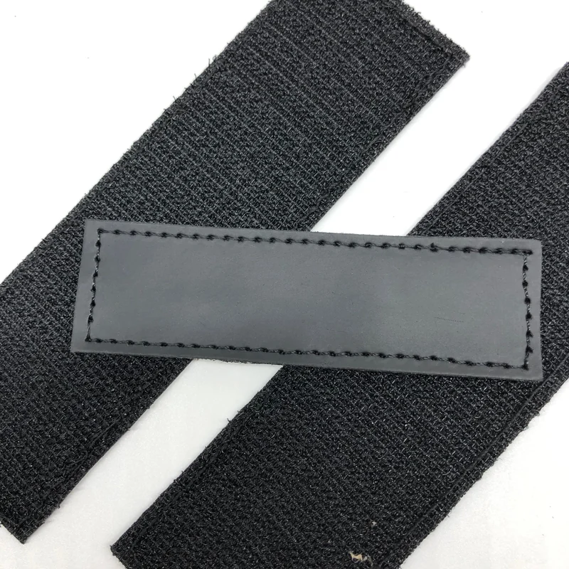 A gray leather label with stitched edges on black fabric.
