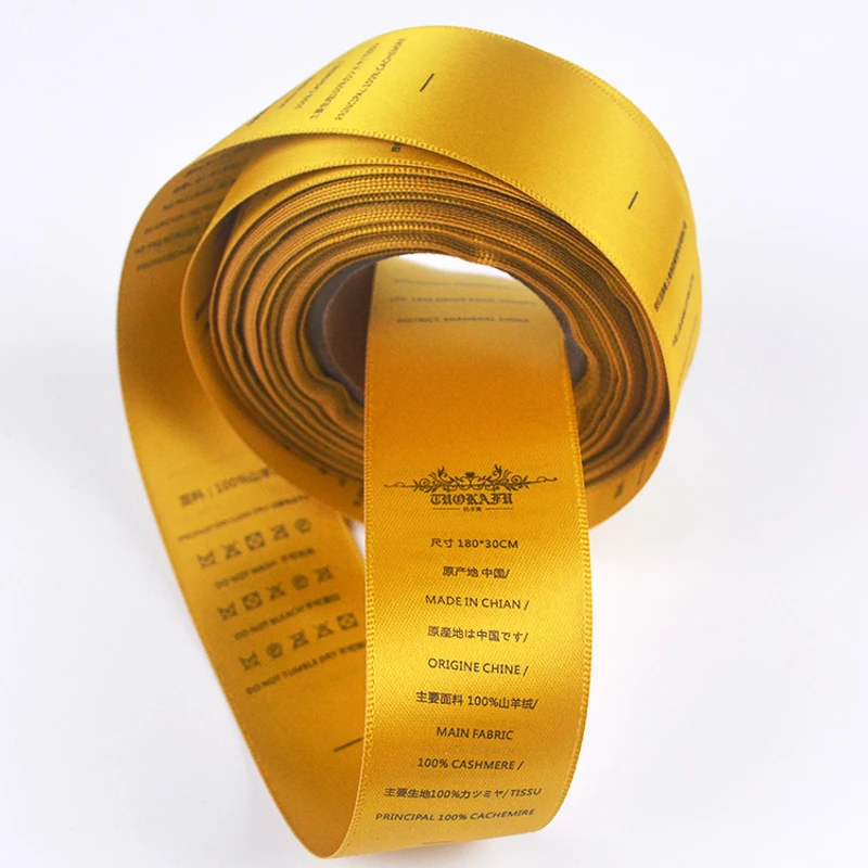 A roll of golden-yellow satin labels printed with garment information.