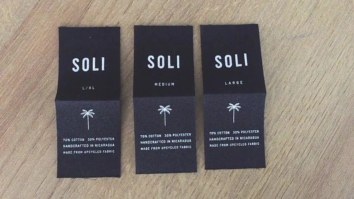 Black fabric labels printed with white logos and care information.