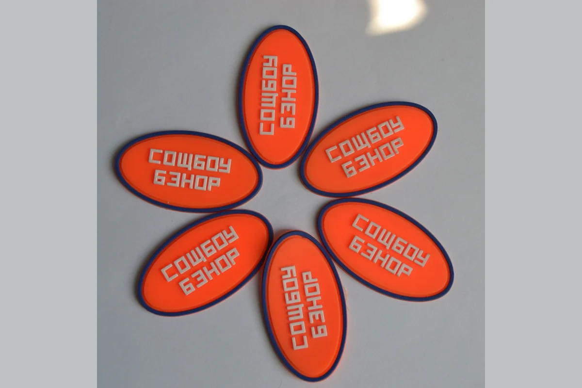 Orange oval molded label samples laid out for a visual check.