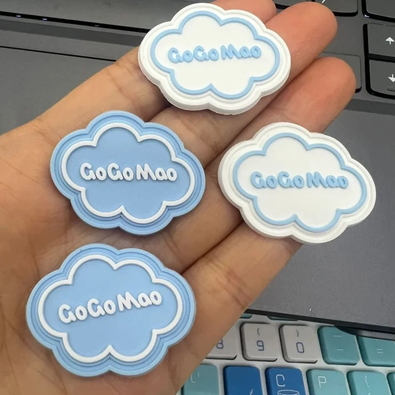 Blue and white cloud-shaped label samples with raised lettering, held on a hand.