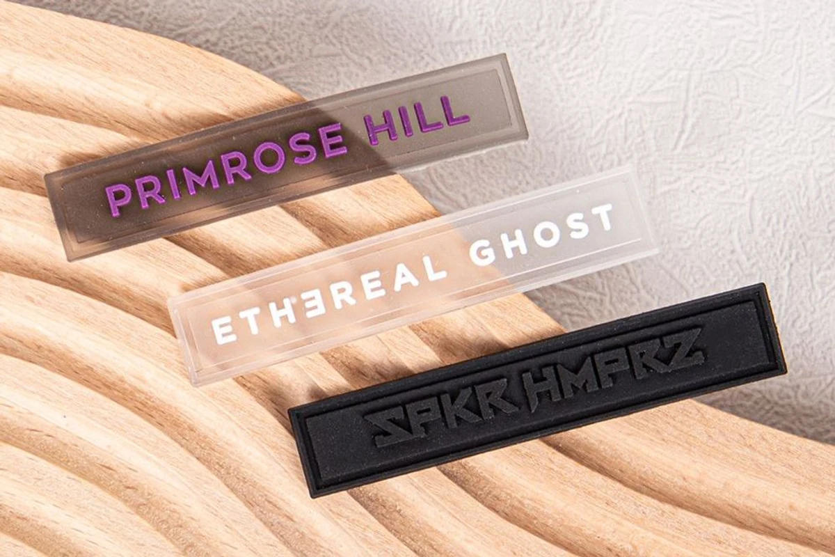 Clear and black rectangular label samples on a textured surface.