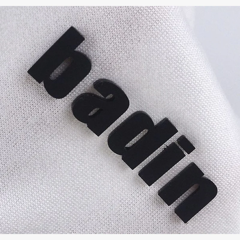 Black raised lettering applied to a light fabric surface.