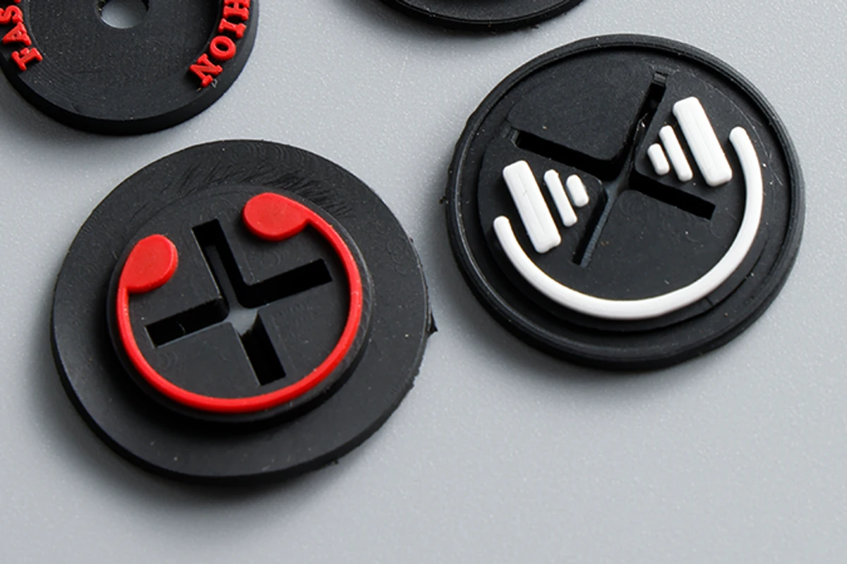 Close-up of round molded label samples with raised face details.