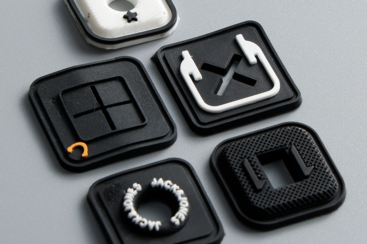 Close-up of molded square label samples with raised borders and relief details.