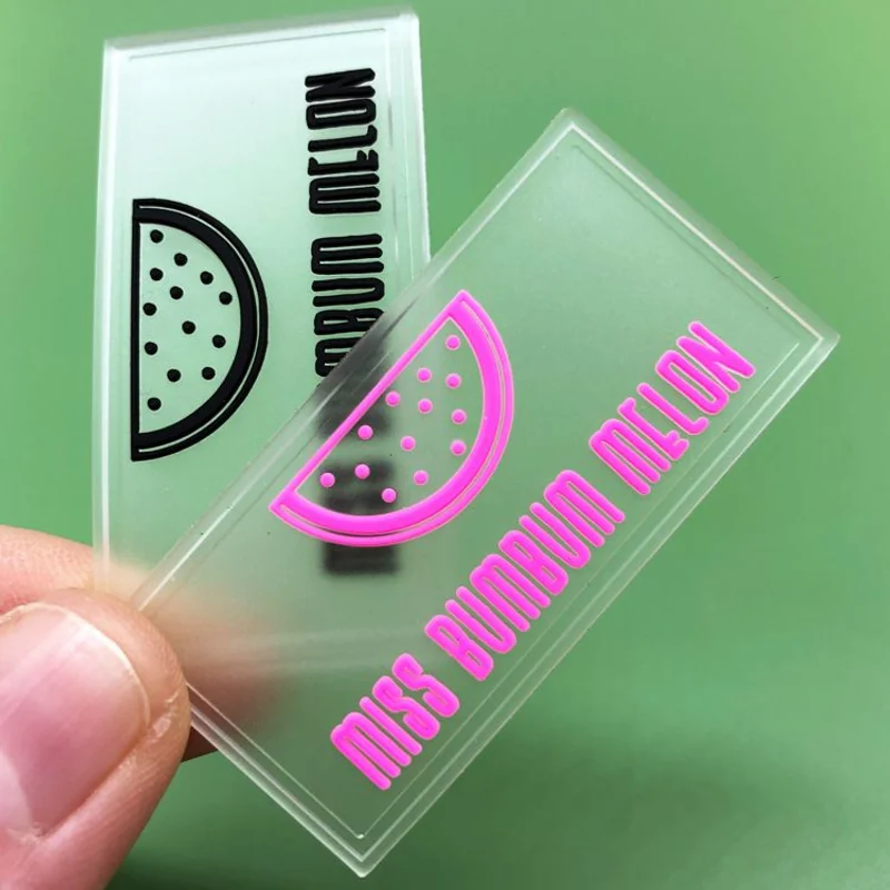 Two clear rectangular label samples with black and pink lettering.