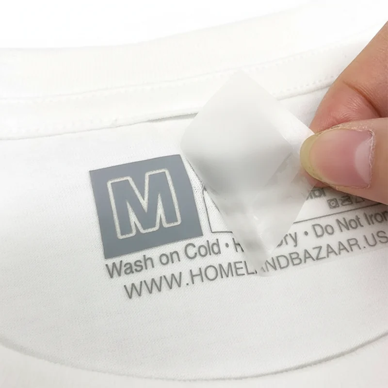 A transfer size label on white garment fabric.