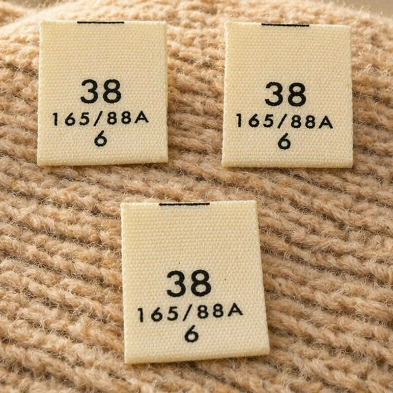 Cream fabric size labels with printed numeric markings.