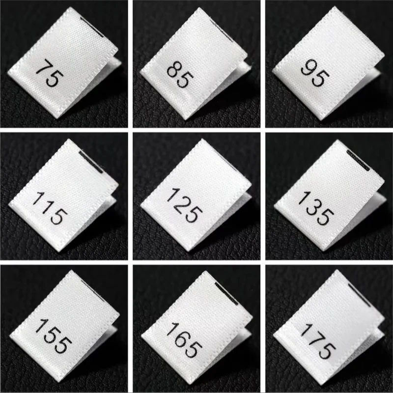 Fabric numeric size label samples on a black textured surface.