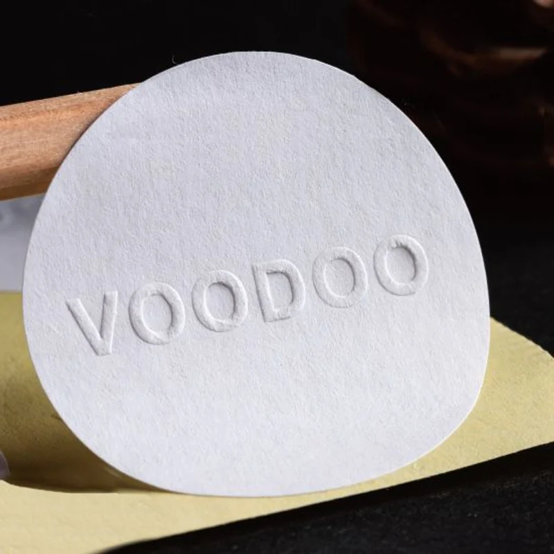 A round white paper sticker with raised brand lettering.