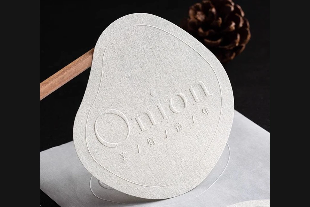 A shaped white paper sticker with raised lettering and an oval border.