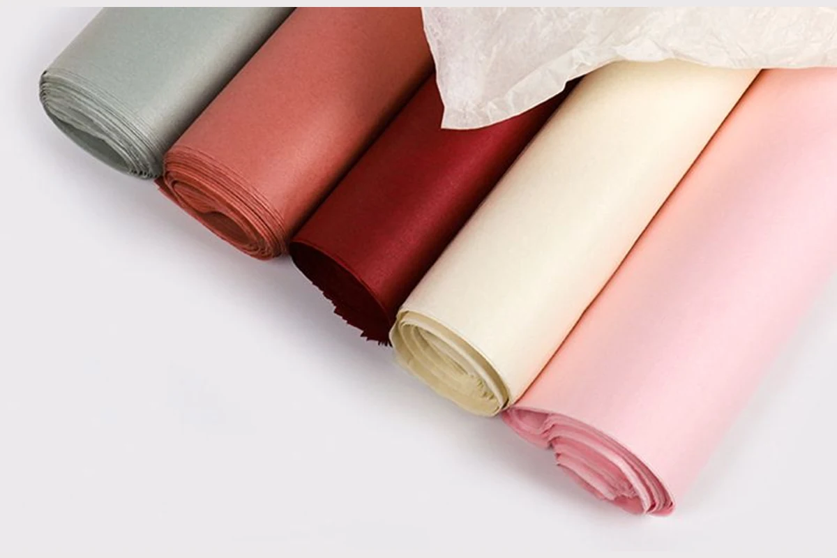 Colored tissue-paper rolls with visible layered ends beneath a loose white sheet.