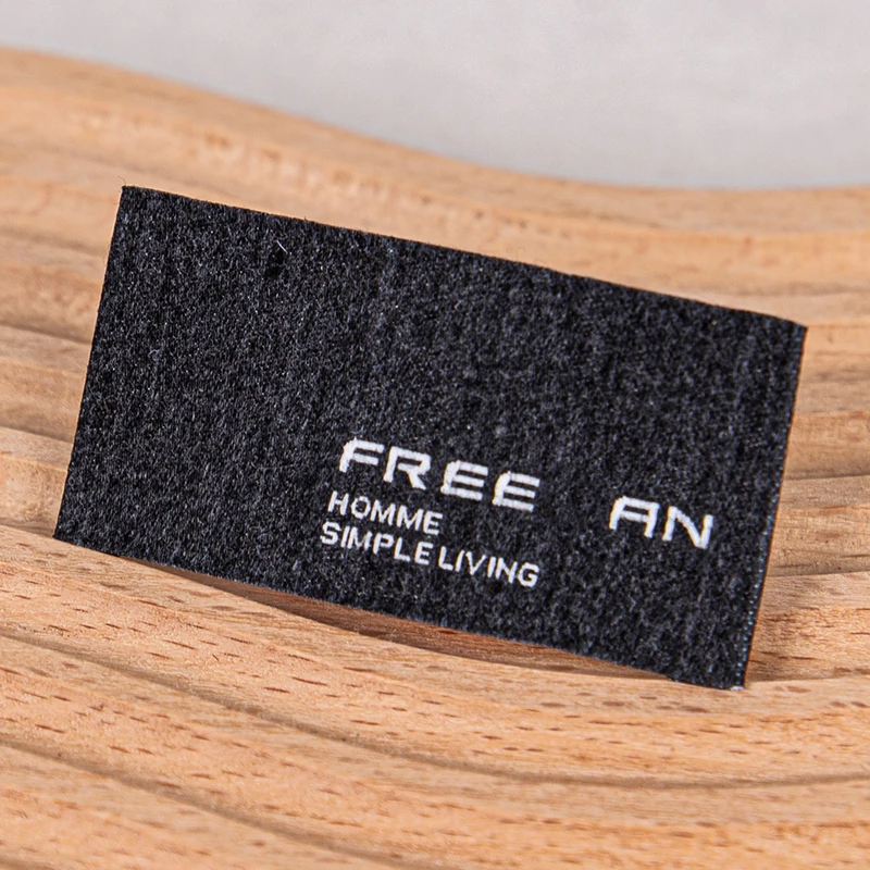 Black rectangular woven label with cut edges.