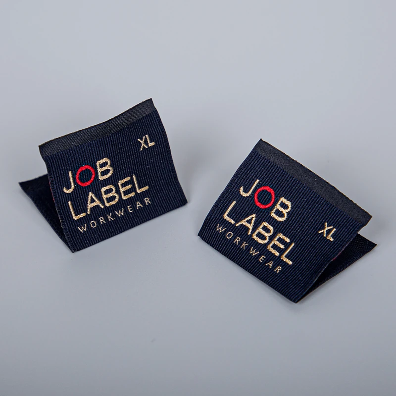 Navy folded woven labels with gold and red lettering.