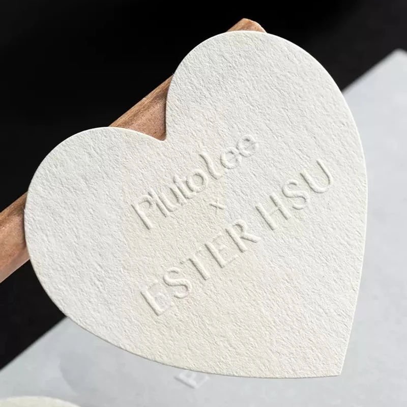 An embossed heart-shaped paper sticker held for a closer look.