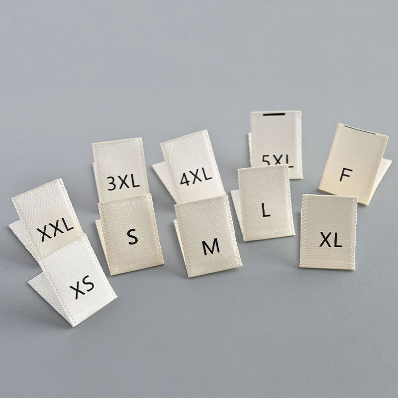 White folded fabric size labels with letter-size markings.