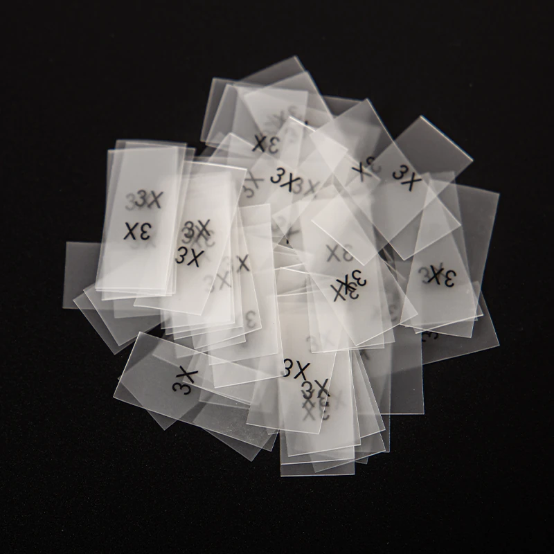 A pile of transparent size stickers with printed letter markings.