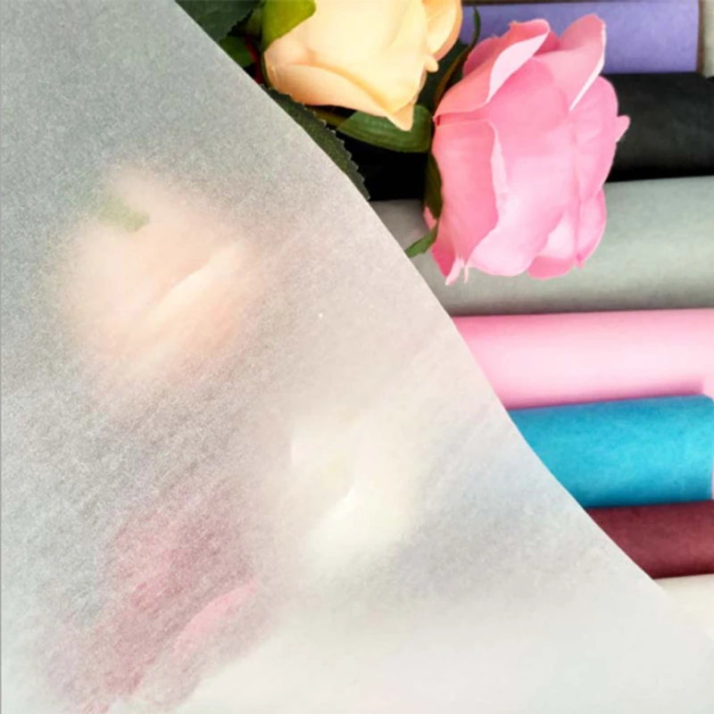 Close-up of translucent wrapping paper over colored sheets and floral samples.