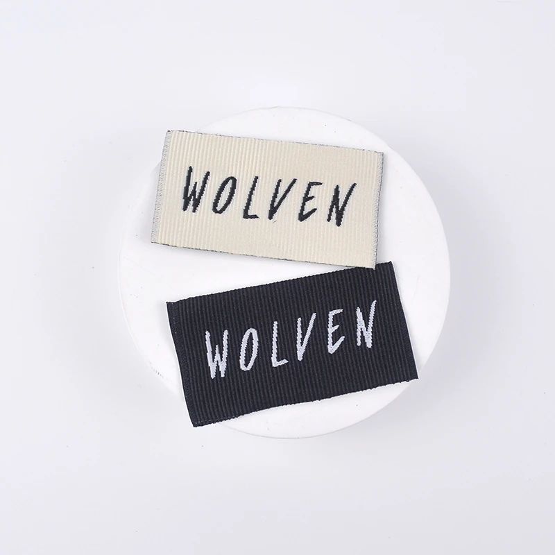White and black folded brand labels with woven lettering.